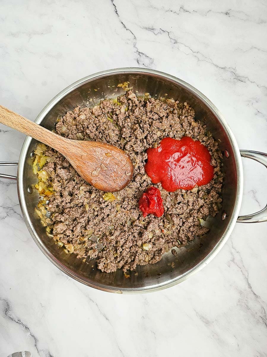 adding tomato paste to browned mince