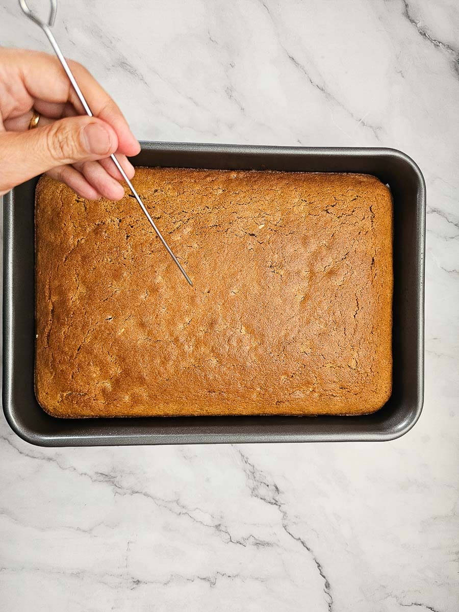 Karidopita - Greek Walnut Cake in baking tray checking if it is baked