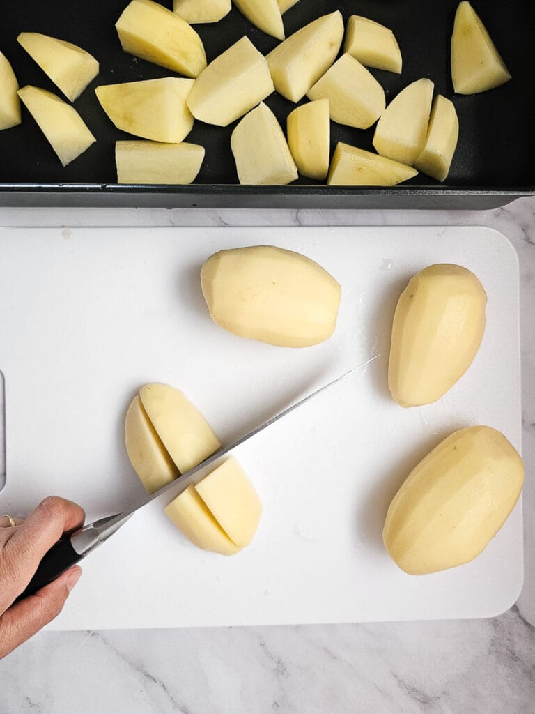cutting potatoes into wedges on chopping board