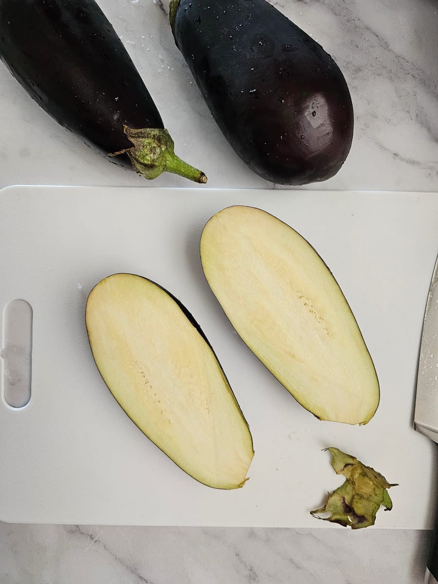 eggplant sliced in half and stems cut