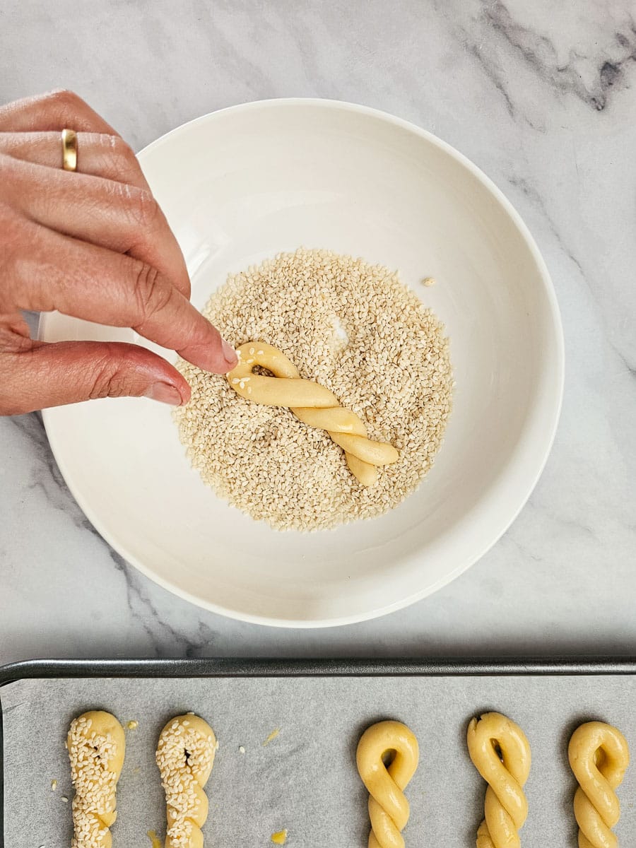dipping koulourakia in sesame seeds before baking
