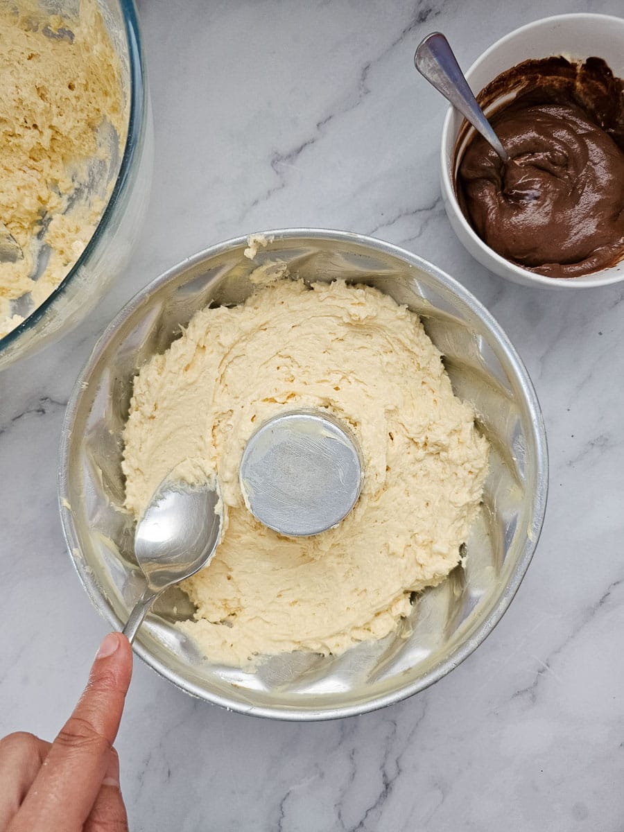 yoghurt cake spooning batter in bundt tin